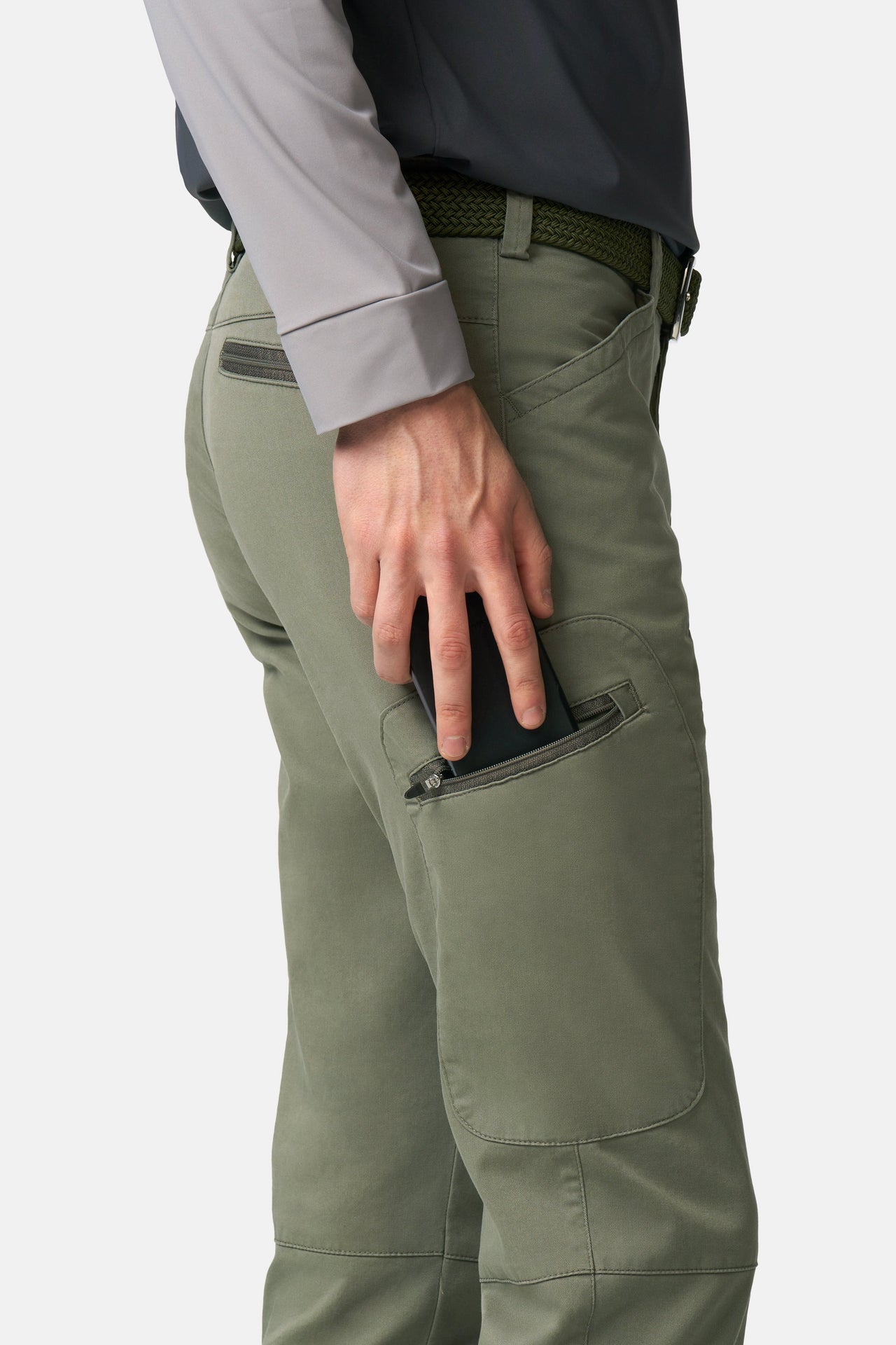 Person wearing green pants with a focus on the pocket area on a white background